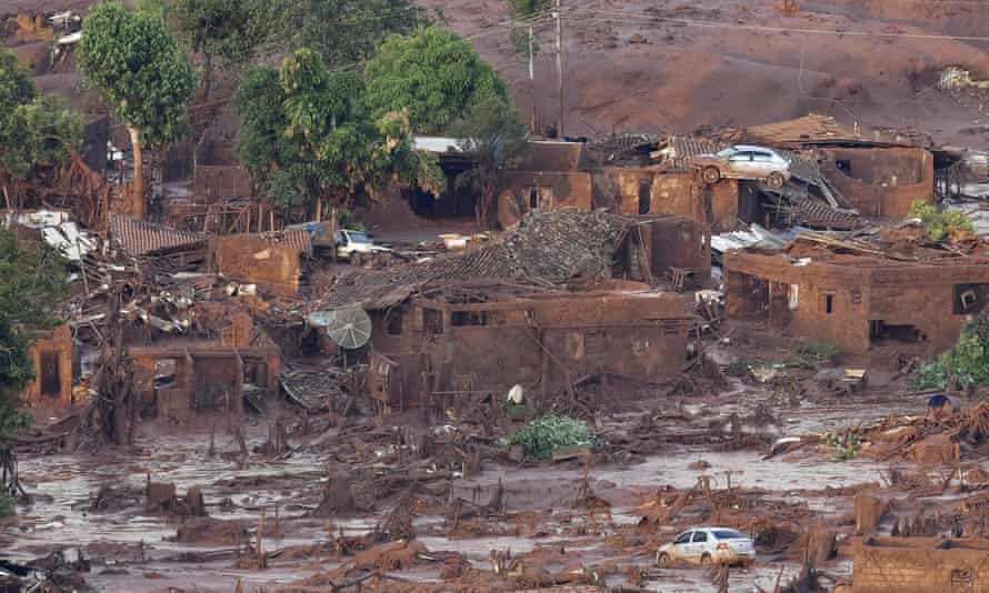Un pueblo después de que un mar de lodo marrón rojizo lo inundara.  Se puede ver un Care posado en una azotea.