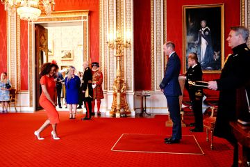 Mel B sonríe mientras hace una reverencia a William mientras recibe MBE frente a su orgullosa madre