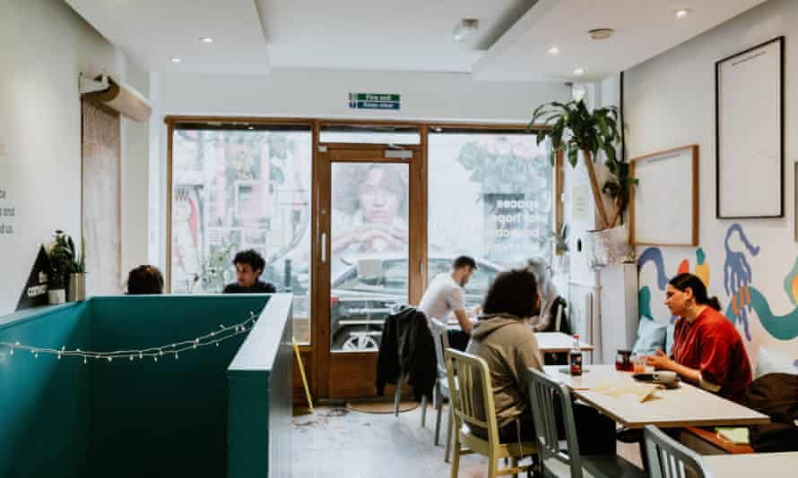 Un café con varias personas sentadas bebiendo y comiendo.