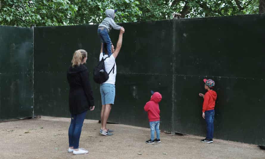 Una familia trata de ver qué sucede dentro del Palacio de Buckingham, que está rodeado por empalizadas de metal.