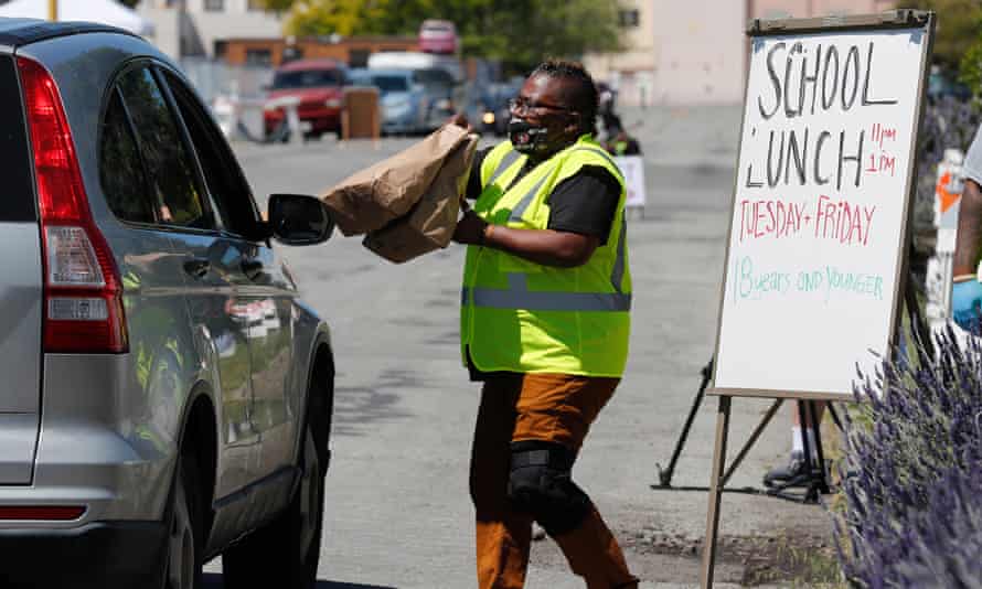 Un voluntario entrega almuerzos escolares a niños en un automóvil en Alameda, California, en abril de 2020.
