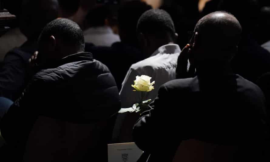Un miembro del público sostiene una rosa blanca durante el servicio conmemorativo.