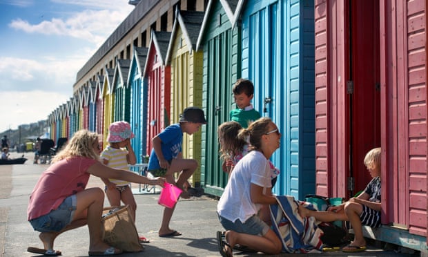 Turistas y casetas de playa en Boscombe Beach, Bournemouth.