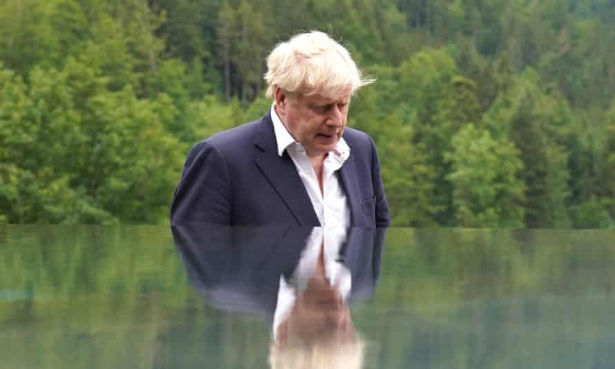 Boris Johnson afuera, con traje pero sin corbata, con la cabeza gacha.