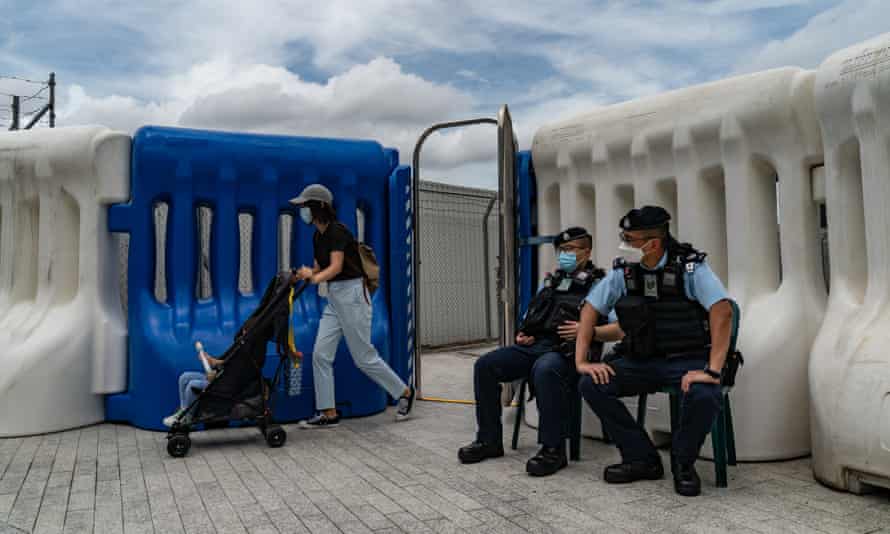 Una mujer que empuja un carrito de bebé pasa el puesto de control de la policía en las afueras de la estación de tren de alta velocidad de West Kowloon antes de la llegada del presidente Xi Jinping.