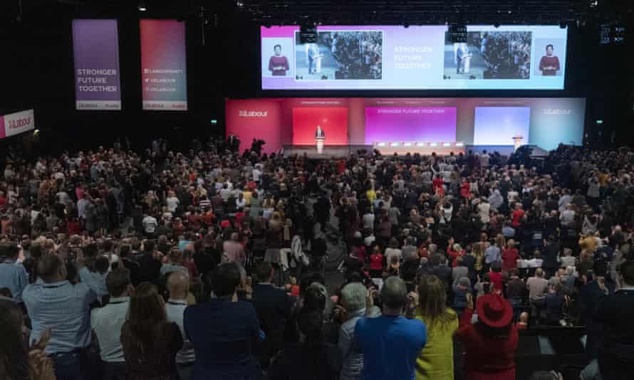 Una multitud en un salón observa a Keir Starmer pronunciar un discurso frente a las pantallas en la Conferencia del Partido Laborista de 2021