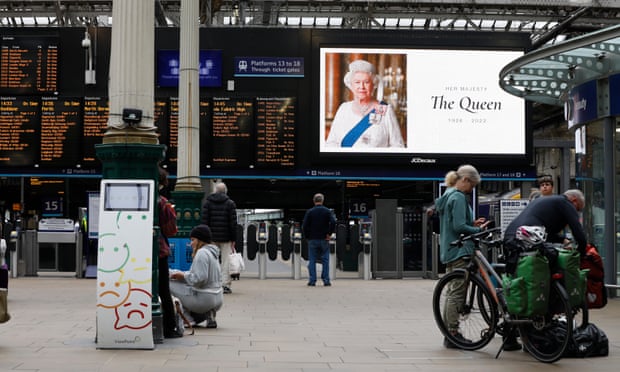 Vestíbulo de la estación de Waverley con gente bulliciosa.  Junto a los paneles de salida hay una gran pantalla de vídeo que muestra un mensaje de condolencias por la Reina