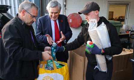 Gordon Brown ayuda con los suministros recolectados por el oficial de vivienda Gary Lynch para un inquilino.