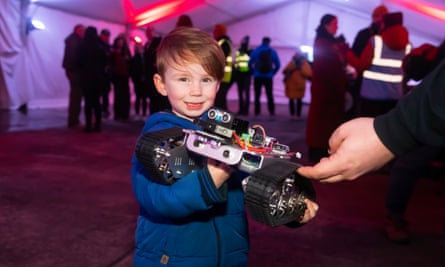 Rory Godfrey, de 4 años, sostiene un robot estilo Mars Rover fabricado por Software Cornwall, uno de los muchos ejemplos de tecnología espacial que se exhiben para los visitantes durante el lanzamiento inaugural del cohete.
