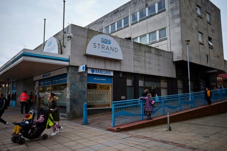 La gente espera o pasa por una esquina del centro comercial Strand en Bootle.