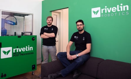 Dos hombres junto al logo de la empresa