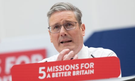 Primer plano de Keir Starmer gesticulando mientras habla en un podio con un cartel adjunto que dice 
